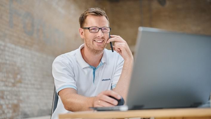 Mann sitzt vor einem Laptop.