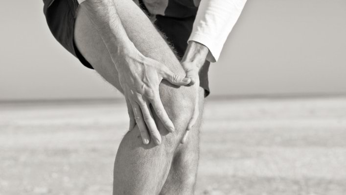 Mann umgreift sein Knie